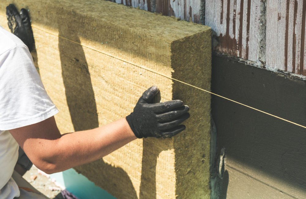 Worker installing rock wool panels on facade wall