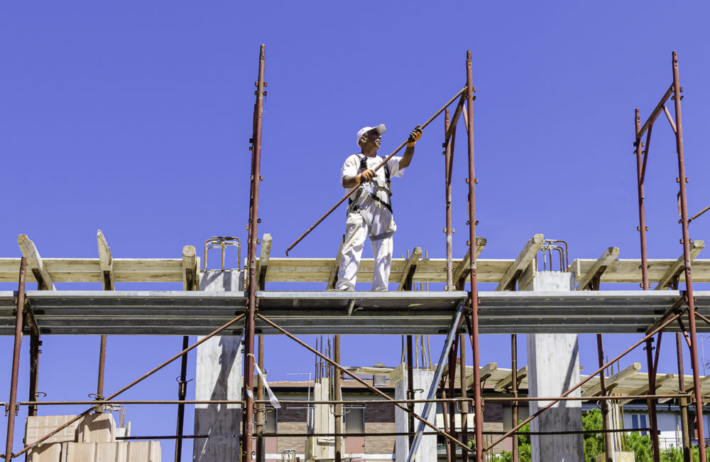 Worker assembling scaffolding on city building